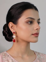 Woman wearing red and silver earrings with a neutral background