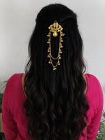 Person with long black hair wearing a gold hair accessory against a white background