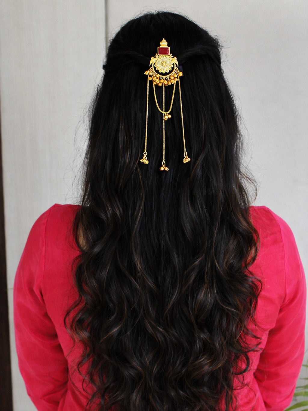 Person with long, wavy hair wearing a decorative hairpin against a neutral background